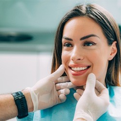 A smiling woman being examined by an emergency dentist in Garland, TX