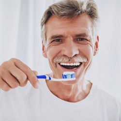 Man in white shirt brushing his teeth