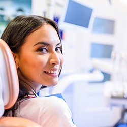 Female patient sitting in dental chair looking back and smiling
