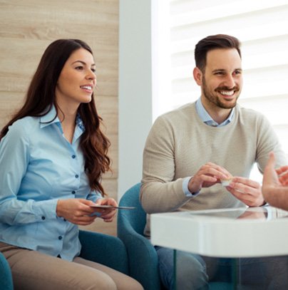 Dentist and couple talking in dental office