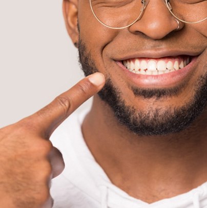 man pointing to his smile who was a good candidate for All-On-4 implants in Garland