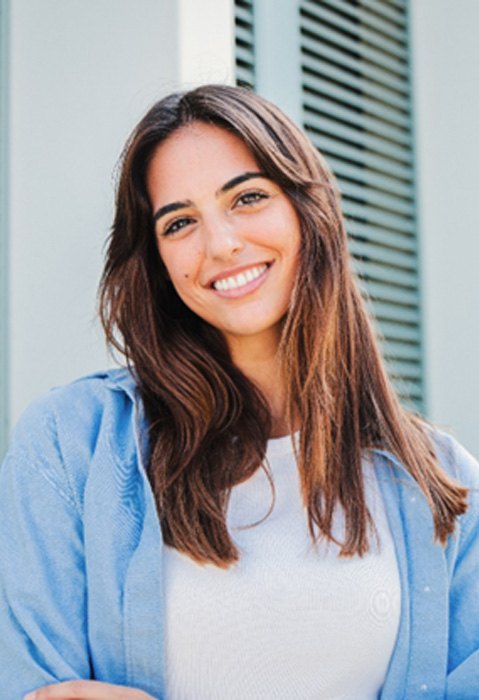 Woman with white teeth smiling while standing outside