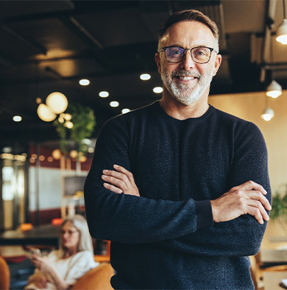 a person smiling with their arms crossed and standing in a coffee shop