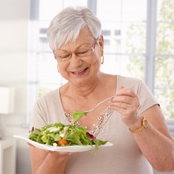 Woman with dentures eating a salad 