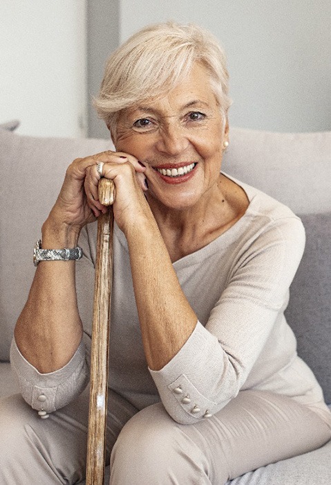 older woman smiling after getting dentures in Garland