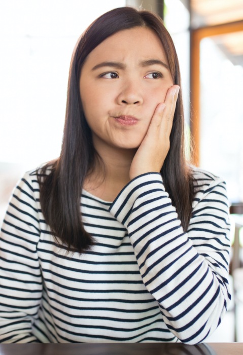 Woman in need of emergency dentistry holding cheek in pain