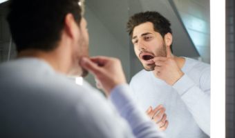 Man with lost dental restoration looking at his smile in mirror