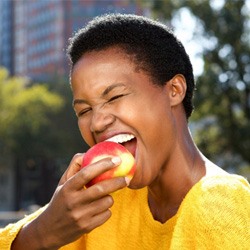 Woman in yellow shirt eating an apple