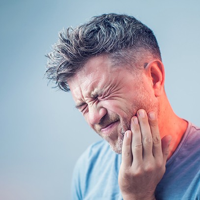 Man squinting eyes closed in pain touching inflamed jaw