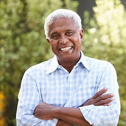 Man with dental implants in North Garland, TX smiling with arms folded