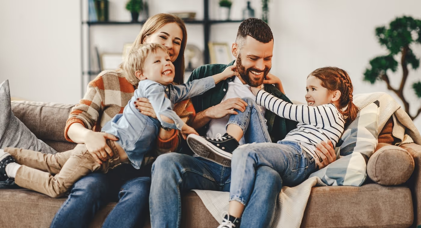Mom and dad playing with son and daughter on couch
