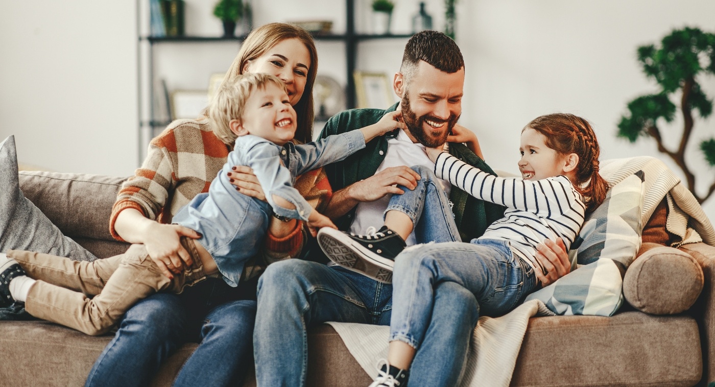 Mom and dad playing with son and daughter on couch