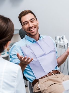 Man in dental chair laughing with his dentist