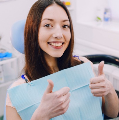 Young woman giving thumbs up after oral cancer screening
