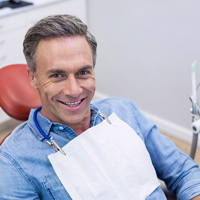 Male patient sitting in dental chair and smiling