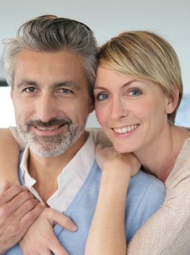 Man and woman smiling after tooth replacement with dental implants