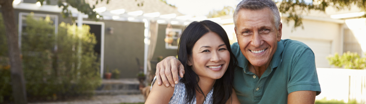 Smiling man and woman standing in their front yard