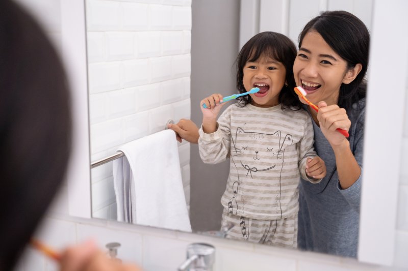 mother and daughter brushing teeth together