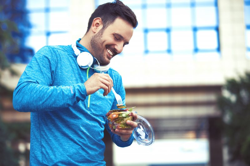 Man eating a salad for good oral health after exercise