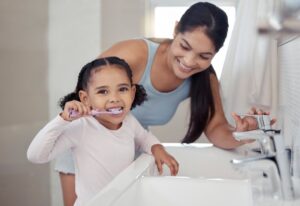 Mom praising daughter during routine toothbrushing